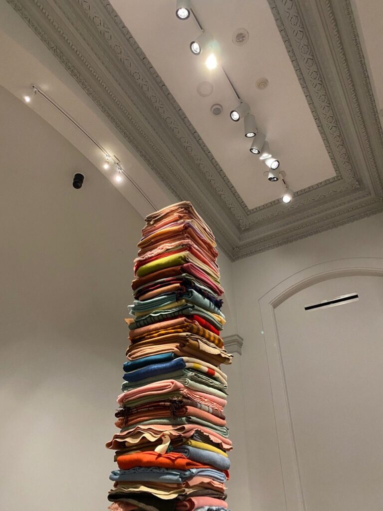 colorful blankets are stacked on top of each other to form a towering pile
