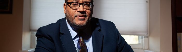 A Black man in a suit in front of a window.