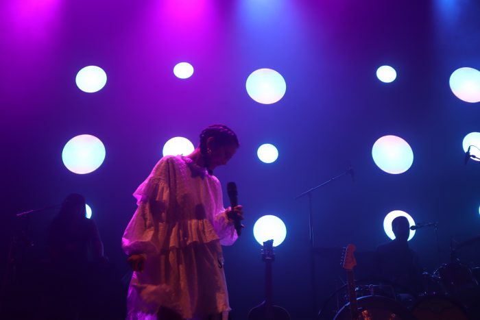 Michelle Zauner looks down in a white dress singing at the Fillmore Silver Spring on July 21.