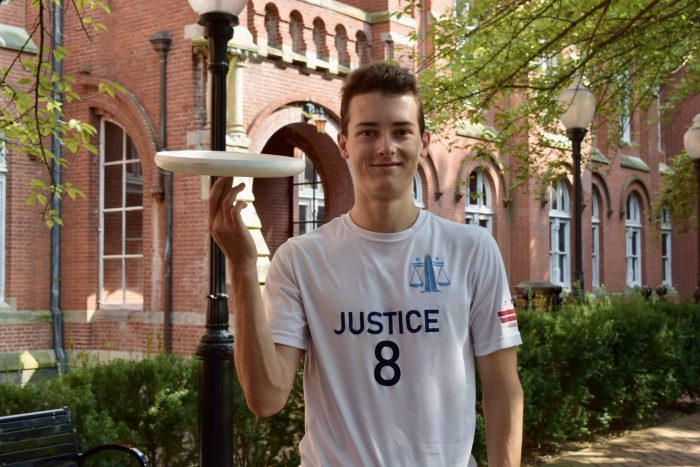 Photo of Paul Taylor holding a frisbee on his finger and smiling in Dahlgren Quad