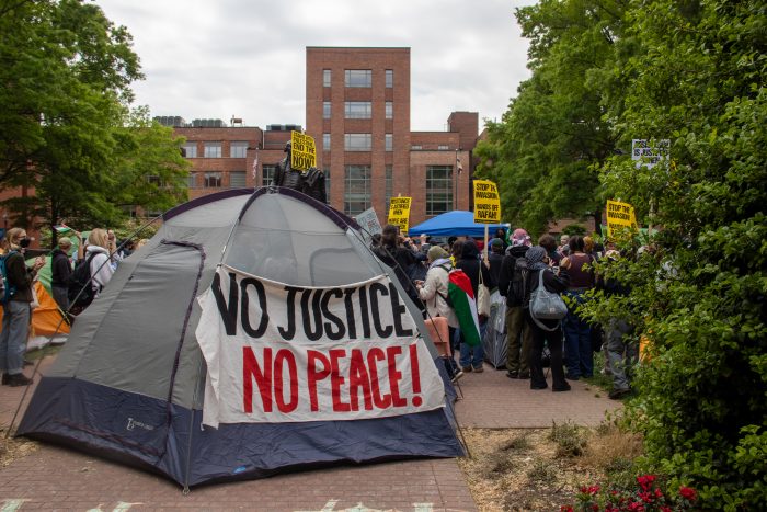 A grey tent at the Gaza solidarity encampment at University Yard on GW's Foggy Bottom campus. A sign on the tent reads, "No justice, No peace!"