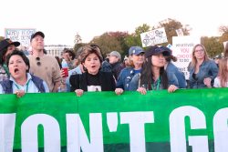 Protesters carry a large green banner that reads, "We won't go back."