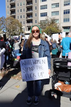 Alice Still stands at the Women's March holding a sign that reads, "WHITE WOMEN: STAND THE FUCK UP."