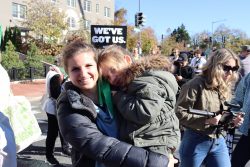 Stacey Kane holds her daughter on her hip at the march. Behind them, a demonstrator holds a sign reading, “We’ve Got U.S.”