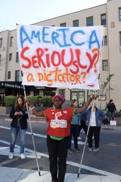 Nadine Feiler holds a sign reading, “America Seriously? A Dictator?” While looking into camera