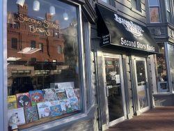 The outside of Second Story Books in DuPont. The store has a black awning with it's name on it, and a window display of books.