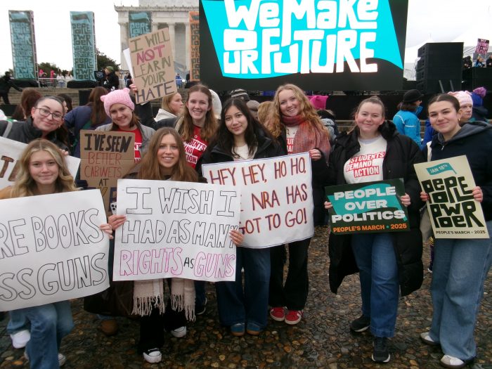 Young students pose with signs reading ‘I wish I had as many rights as guns’ and ‘hey hey, ho ho, the NRA has got to go’