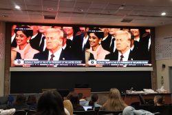 Students watch the inauguration in a Reiss auditorium. Trump is shown on two large screens at the front of the room.