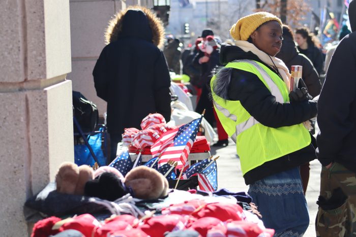 A table displays American flags, MAGA hats, and other inauguration-related merch.