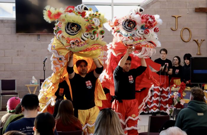 Performers put on a lion dance. There are to dragon props: the one on the left is yellow, and the one on the right is red. Under the head of each dragon, a performer can be seen lifting up the dragon prop.