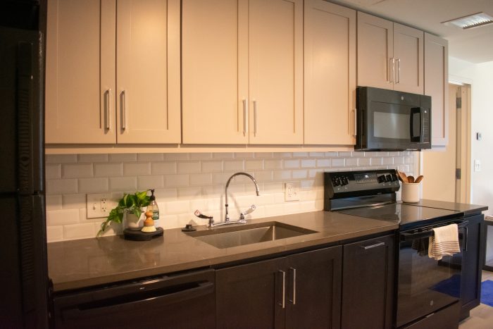 Part of the kitchen in a redeveloped apartment, featuring an oven, fridge, and cabinets.