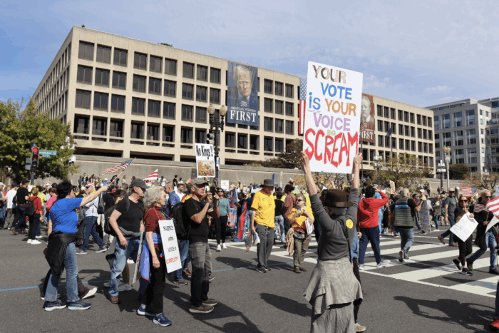 Protestors hold up signs in front of the Department of Labor.