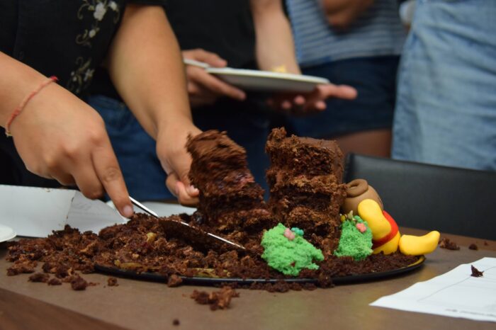 A close-up of a chocolate cake being cut and distributed.